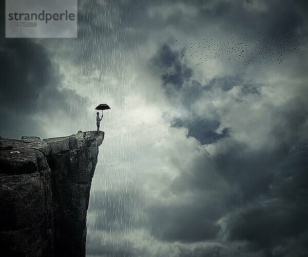 Mann mit Regenschirm steht am Rande der Klippe und ruft den Regen. Mysteriöser Ort über den Wolken
