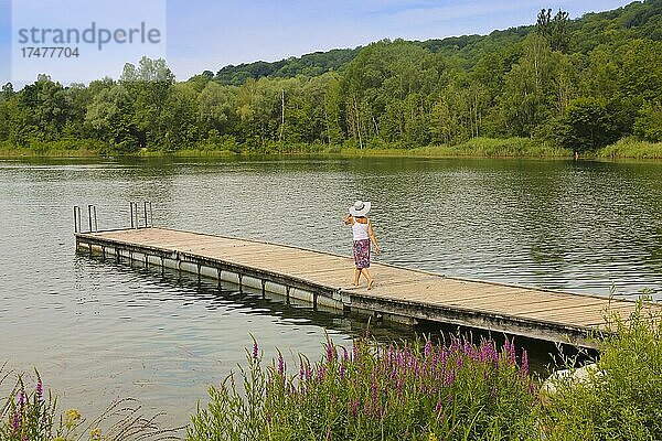 Frau mit Sonnenhut und Rock läuft auf Steg  Pfuhler See  Badegewässer  Neu-Ulm  Bayern  Deutschland  Europa