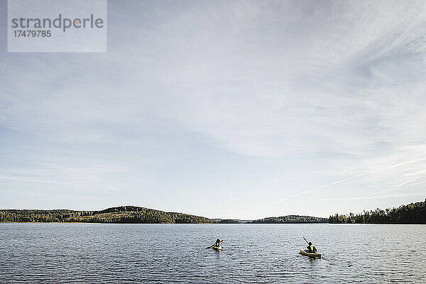 Paar fährt am Wochenende Kajak auf dem See gegen den Himmel