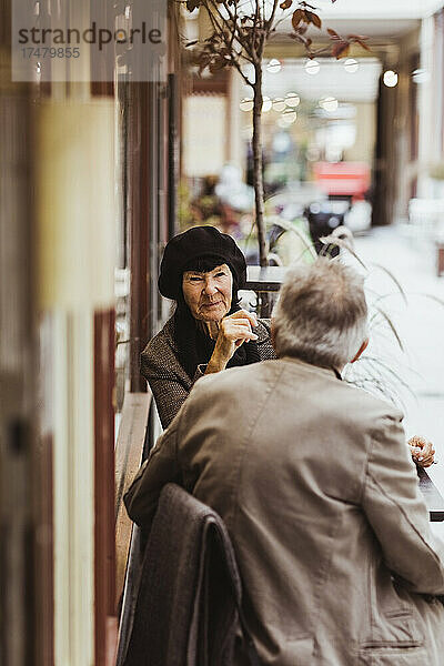 Ältere Frau im Gespräch mit einem Mann in einem Straßencafé im Urlaub