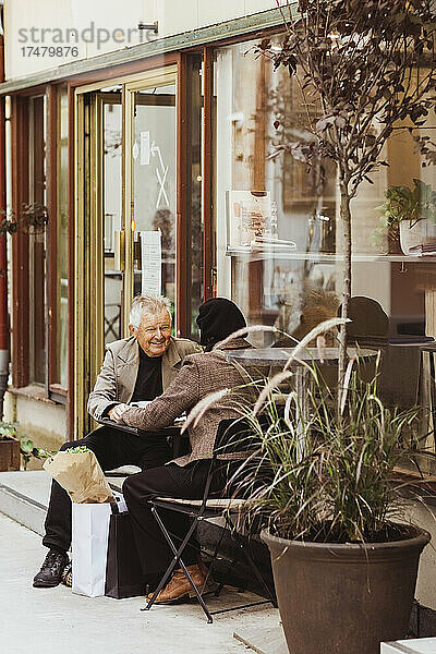 Älterer Mann und Frau sitzen in einem Straßencafé in der Stadt