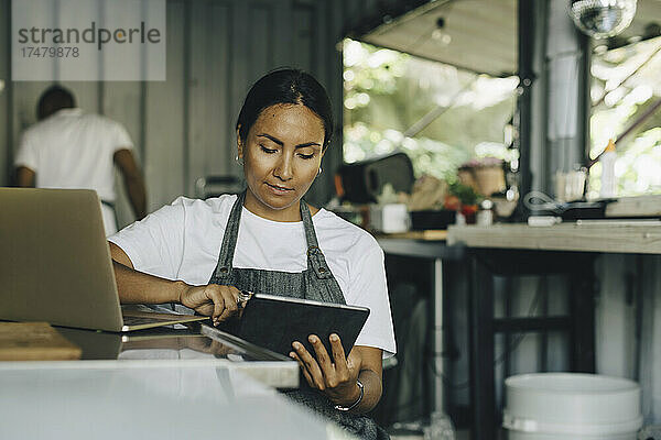 Besitzerin arbeitet an digitalem Tablet im Foodtruck