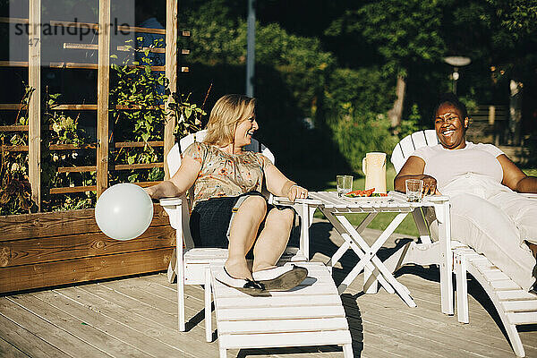 Fröhliche Freundinnen verbringen Freizeit auf der Terrasse an einem sonnigen Tag