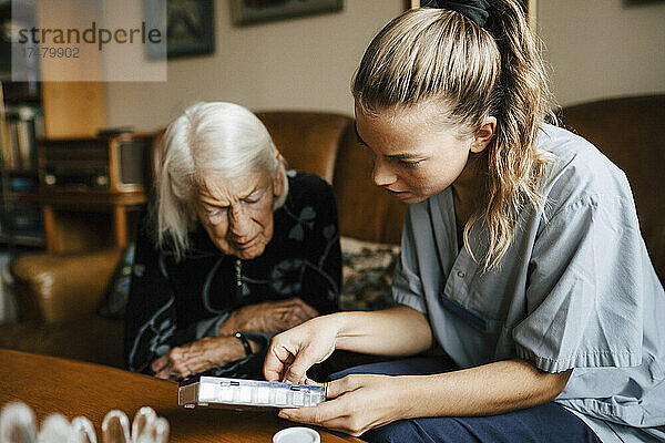 Krankenschwester erklärt einer älteren Frau zu Hause die Medikamentendosis