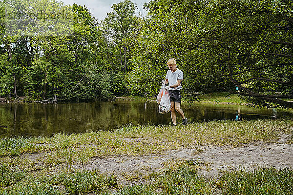 Junger männlicher Freiwilliger reinigt Plastikmüll am Teich