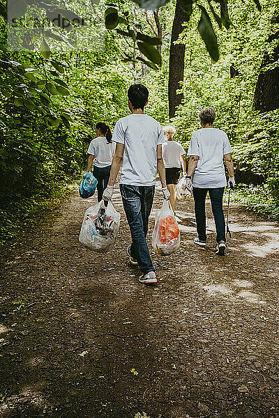 Rückansicht von weiblichen und männlichen Freiwilligen mit Plastikmüll im Park