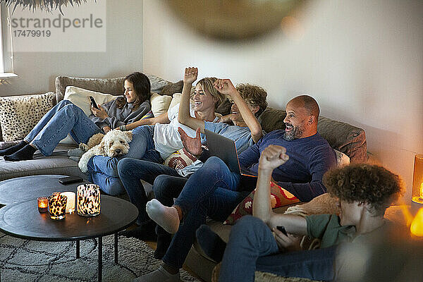 Die Familie jubelt beim gemeinsamen Fernsehen im heimischen Wohnzimmer