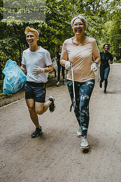 Fröhliche Frau und Mann beim Joggen mit Plastiktüte im Park