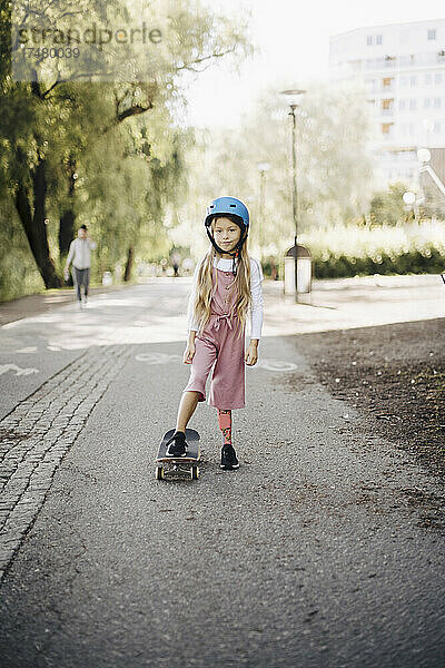 Mädchen fährt Skateboard auf der Straße im Park