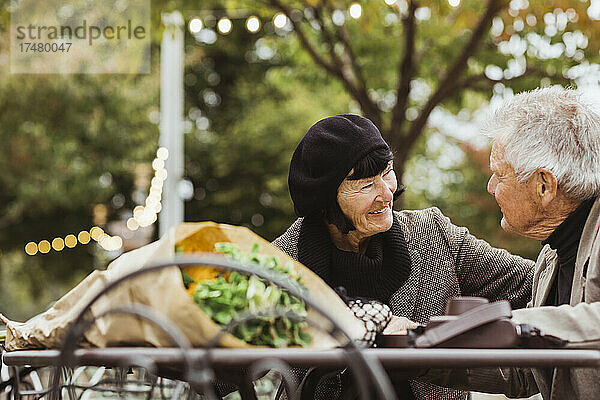 Lächelnde ältere Frau  die einen Mann im Park im Urlaub betrachtet