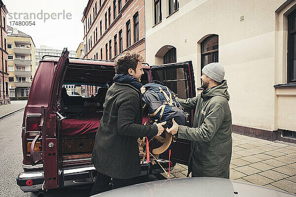 Reife männliche Freunde beladen das Gepäck im Wohnmobil während einer Autoreise