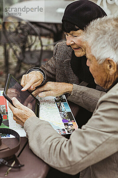 Älterer Mann und Frau nutzen GPS-Navigation über ein digitales Tablet am Tisch