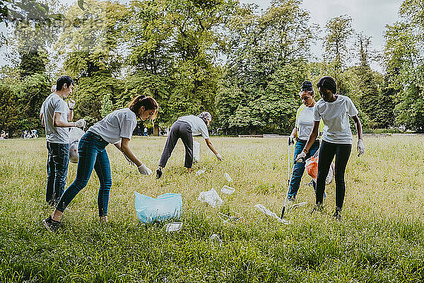 Männliche und weibliche Freiwillige reinigen Plastik im Park
