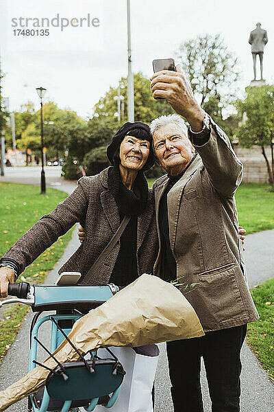 Älteres Paar  das am Wochenende im Park ein Selfie mit einem Elektrofahrrad per Smartphone macht