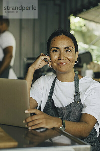 Porträt einer lächelnden Verkäuferin mit Laptop in einem Imbisswagen