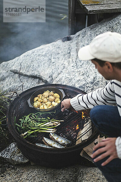 Erwachsener Mann bei der Zubereitung von Essen auf einem Grill auf einer Insel