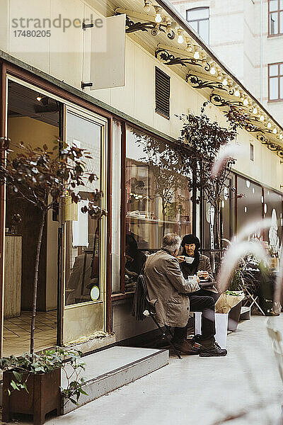 Älteres Paar trinkt Kaffee und sitzt zusammen vor einem Café