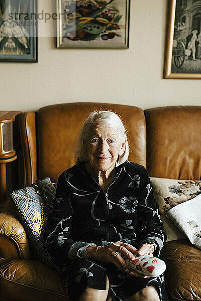 Porträt einer älteren Frau  die auf dem Sofa im Wohnzimmer sitzt