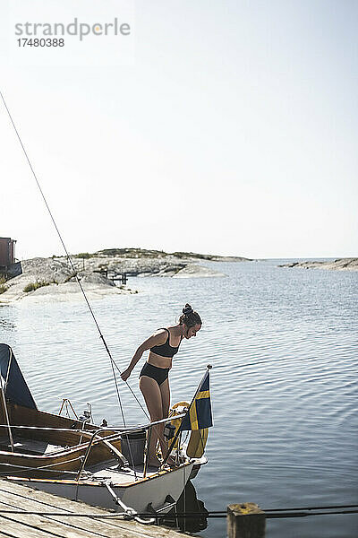Mittlere erwachsene Frau im Bikini auf einem Segelboot an einem sonnigen Tag