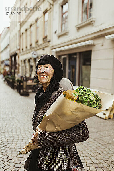 Lächelnde ältere Frau mit Blumenstrauß auf der Straße