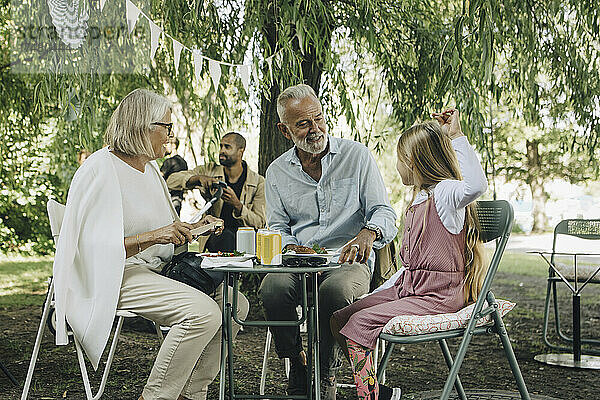 Enkelin isst Straßenessen mit Großeltern im Park