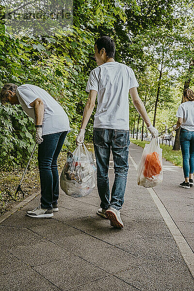 Männliche und weibliche Freiwillige säubern einen Fußweg von Plastik