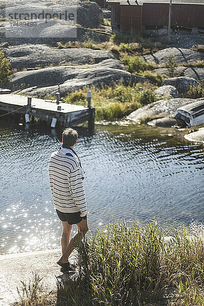 Mittlerer erwachsener Mann  der an einem sonnigen Tag am Fluss spazieren geht