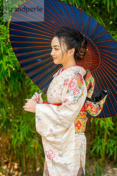 Nachdenkliche Frau trägt Kimono und hält Sonnenschirm