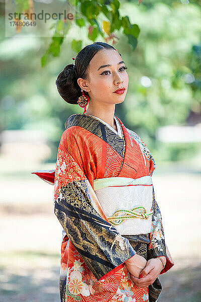 Nachdenkliche Frau im Kimono steht im Park