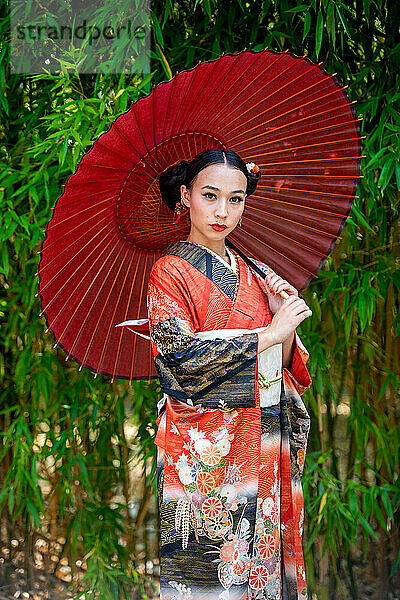 Porträt einer Frau im Kimono und mit Sonnenschirm im Park