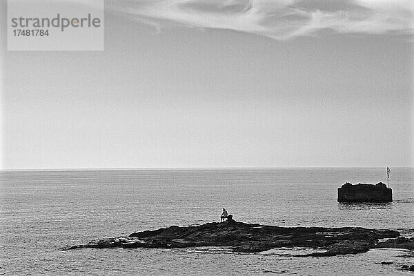 Mann sitz alleine auf kleiner Felsinsel  Felseninsel  Mann am Meer  Einsamkeit  Nachdenklichkeit  Robinson-Syndrom  Robinson-feeling  Villaricos  Almeria  Andalusien  Spanien  Europa