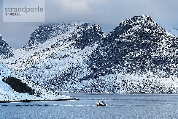 Fischerboot in winterlicher skandinavischer Landschaft am Fjord  Meer  Berge  Schnee  Ramberg  Nordland  Lofoten  Norwegen  Europa