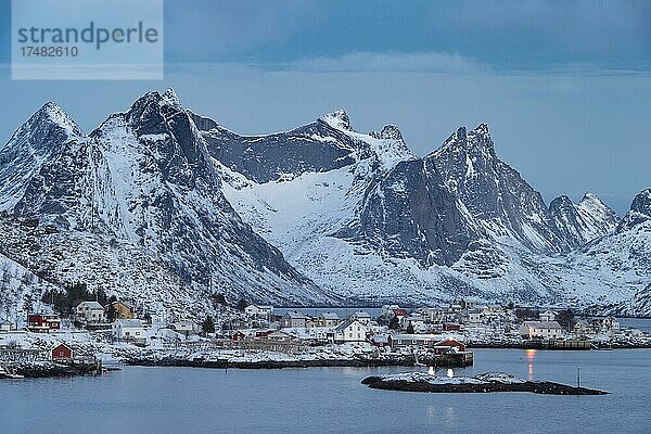 Winterliche skandinavische Landschaft mit erleuchteten Häusern  Meer  Berge  Schnee  Reine  Nordland  Lofoten  Norwegen  Europa