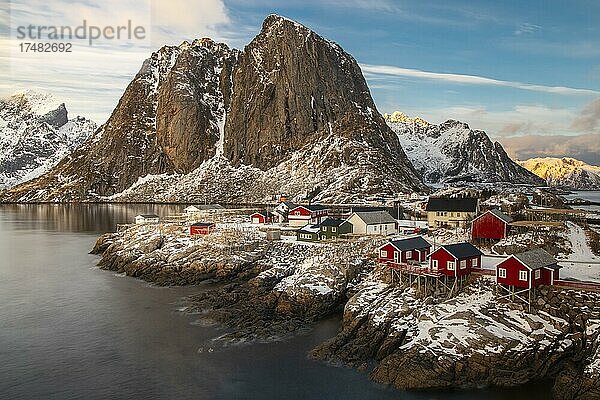 Winterliche skandinavische Landschaft mit roten Häusern  Meer  Berge  Schnee  Hamnøy  Nordland  Lofoten  Norwegen  Europa