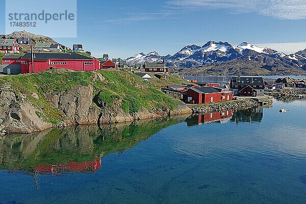 Häuser am seichten Ufer eines Fjordes  schneebedeckte Berge  Tasilaq  Arktis  Ostgrönland  Grönland  Dänemark  Nordamerika