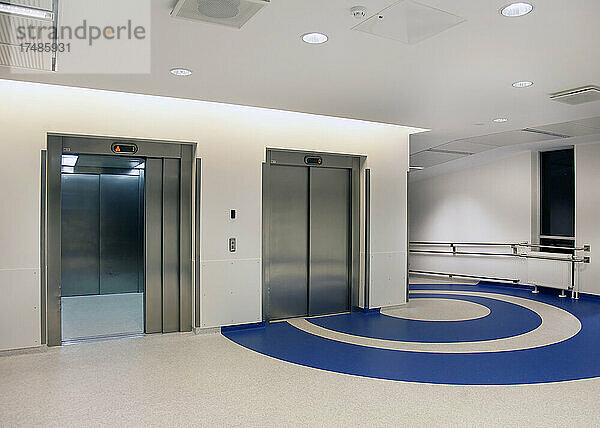 Aufzüge im Atrium eines neuen modernen Krankenhauses  blaue Muster auf dem Boden