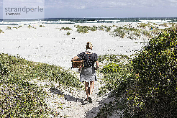 Erwachsene Frau mit Picknickkorb am Grotto Beach  Hermanus  Westkap  Südafrika.