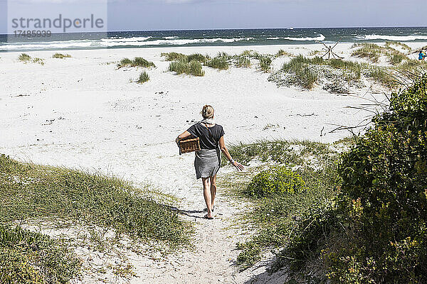 Erwachsene Frau mit Picknickkorb am Grotto Beach  Hermanus  Westkap  Südafrika.