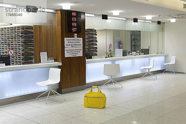 Wartebereich und Empfangsschalter in einem modernen Krankenhaus  mit Schildern und elektronischer Anzeige Gelber Sack.