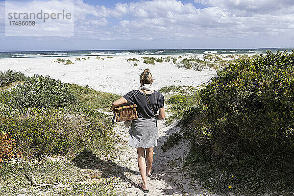 Erwachsene Frau mit Picknickkorb am Grotto Beach  Hermanus  Westkap  Südafrika.