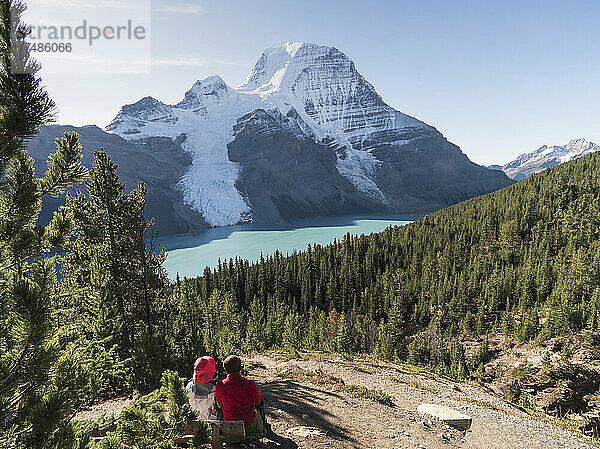Zwei Personen ruhen sich an einem Wanderweg aus  Blick auf den Mount Robson und die Rockies.