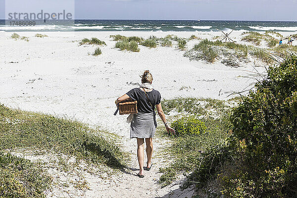 Erwachsene Frau mit Picknickkorb am Grotto Beach  Hermanus  Westkap  Südafrika.