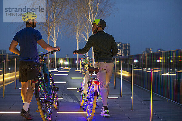 Männer mit beleuchteten Fahrrädern auf einem städtischen Fußweg  London  UK