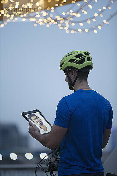 Mann mit Fahrradhelm führt Videochat mit einem Freund auf einem digitalen Tablet-Bildschirm