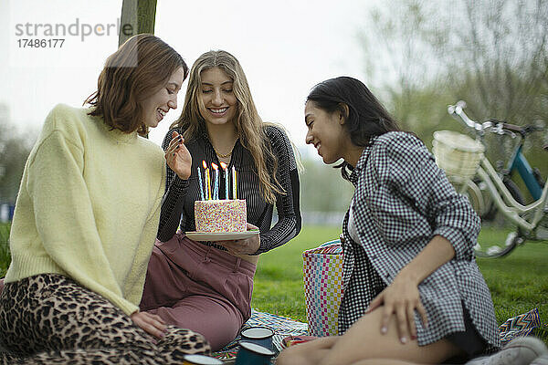 Glückliche junge Frauen Freunde feiern Geburtstag mit Kuchen im Park