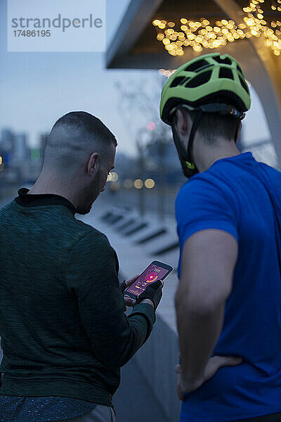 Männer mit Fahrradhelm  die nachts ihr Smartphone benutzen