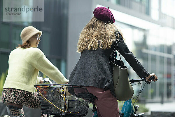 Stilvolle junge Frauen Freunde fahren Fahrräder in der Stadt