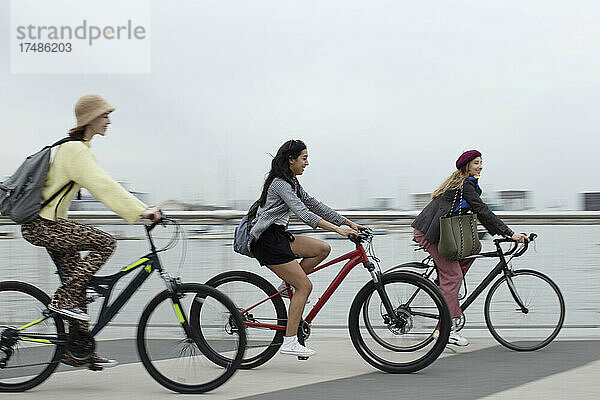 Junge Freundinnen fahren mit dem Fahrrad am Wasser entlang
