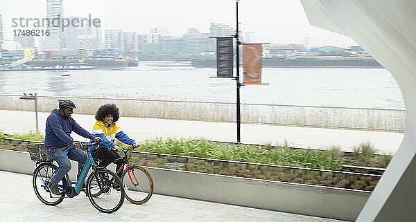 Vater und Sohn fahren mit dem Fahrrad am Wasser entlang in der Stadt London  UK