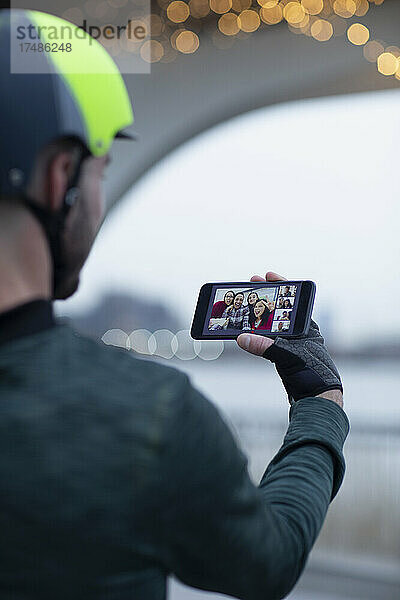 Mann führt Videochat mit seiner Familie auf dem Bildschirm seines Smartphones